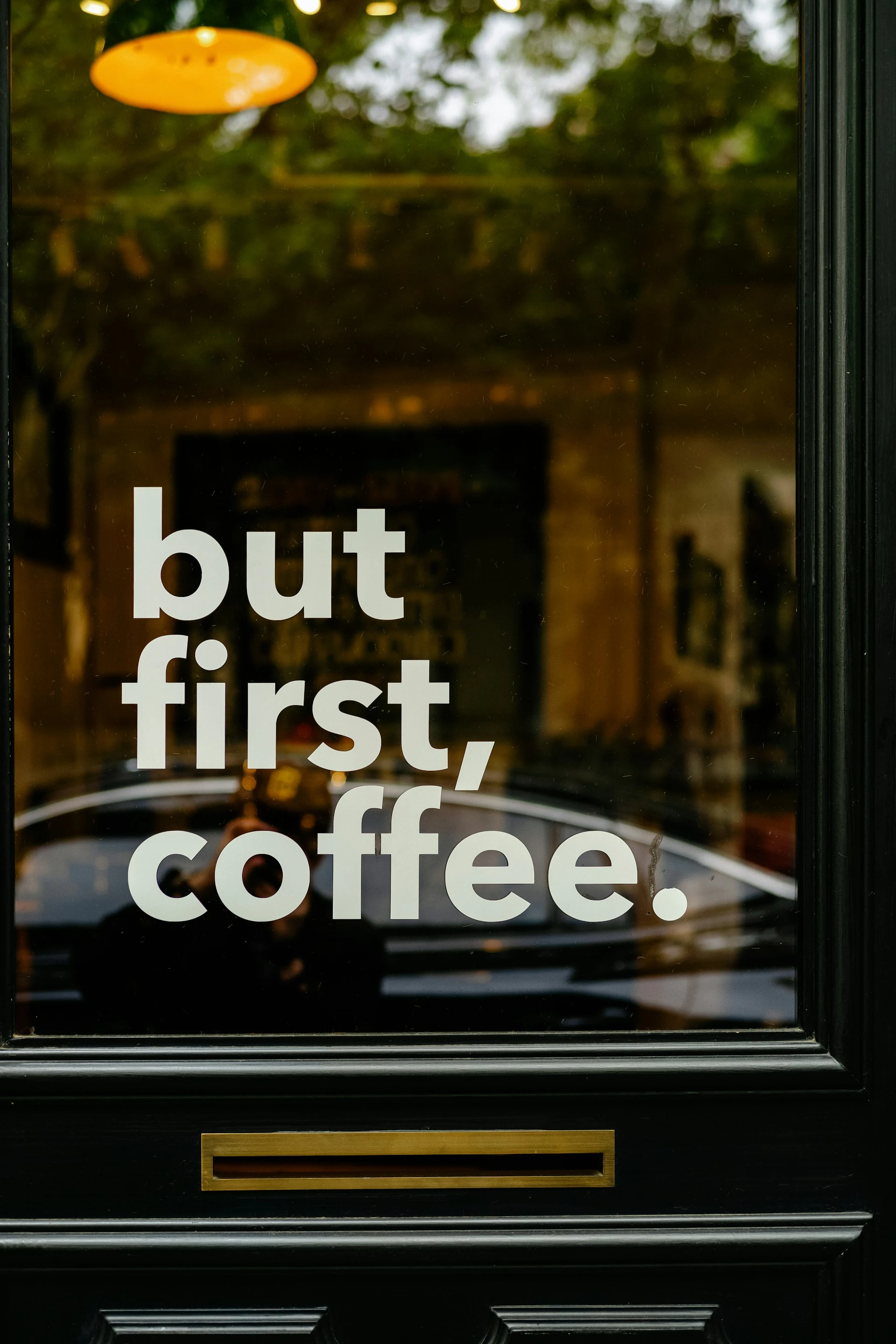 Coffee shop window reading but first, coffee